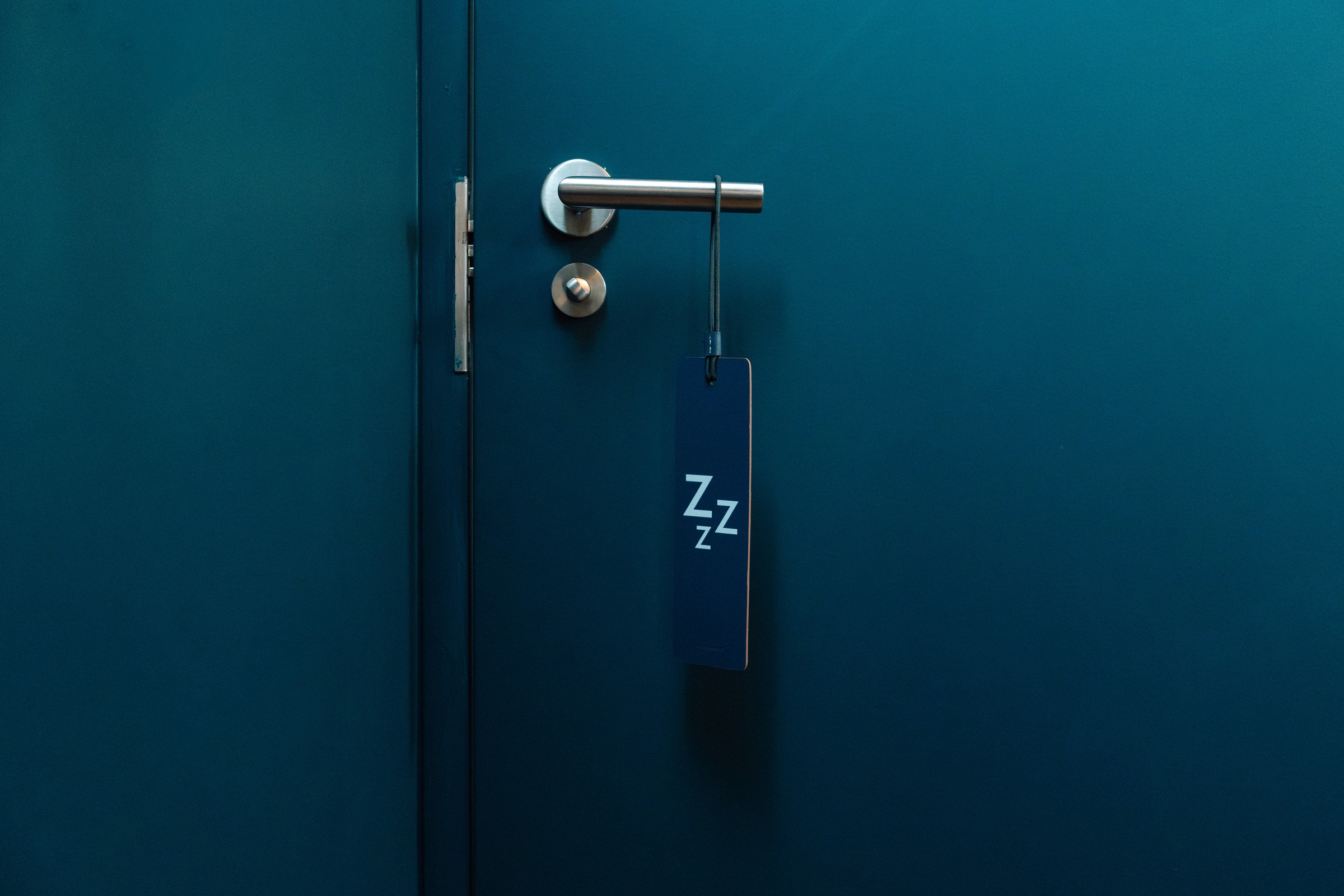 Blue hotel door with a hanging guest sign