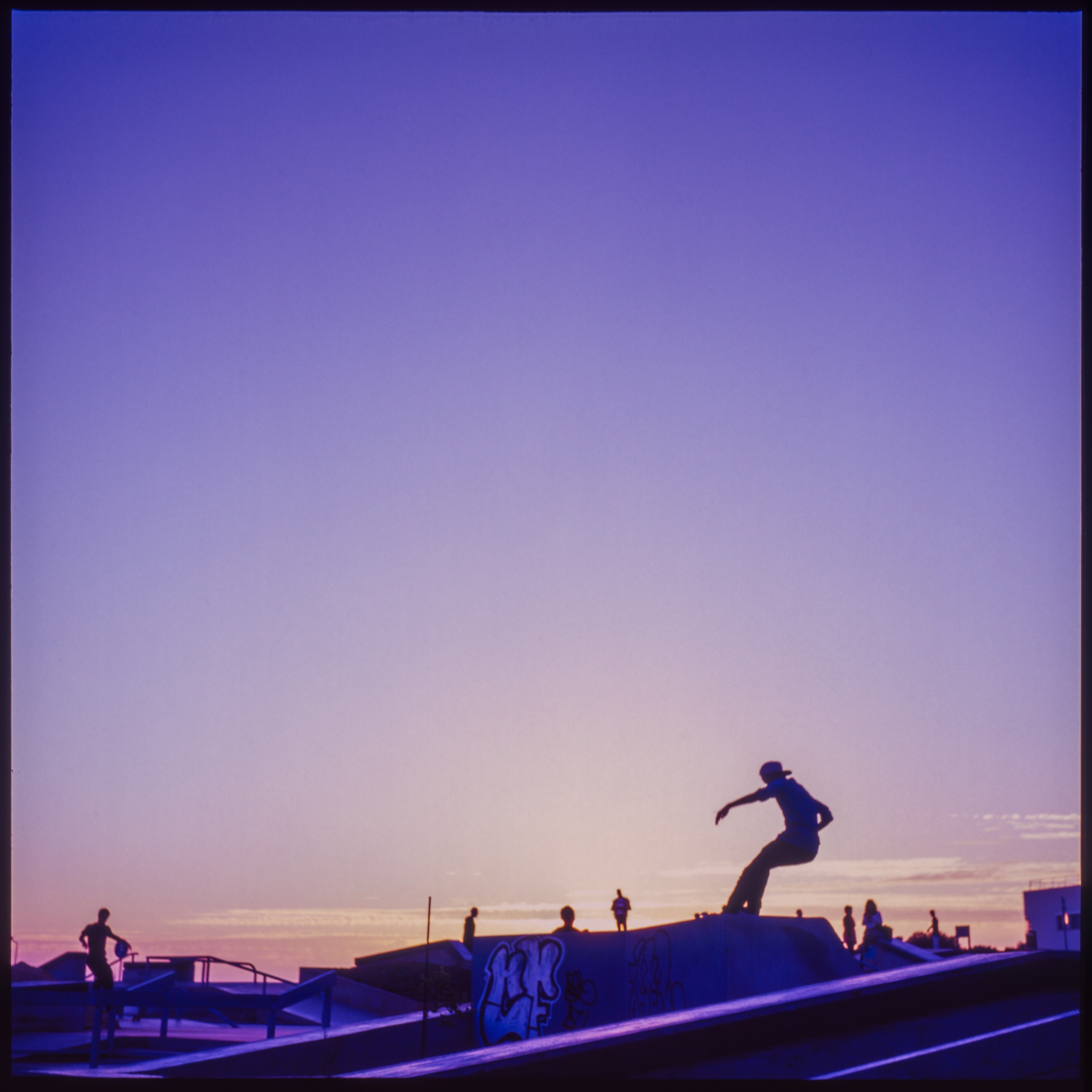 A skateboarder silhouetted against a violet and peach evening sky.