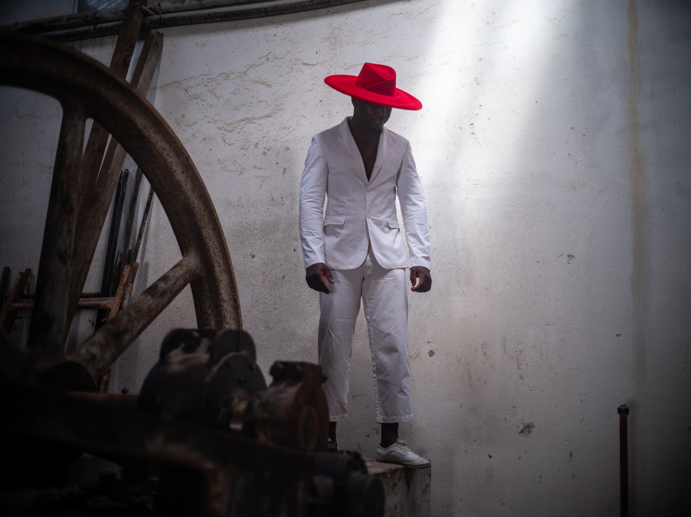 Man in a white suit and red hat beside industrial machinery