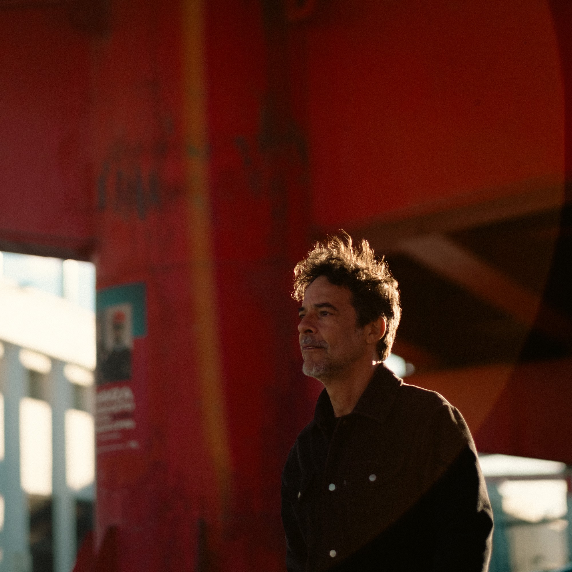 Portrait against red architecture, with warm rim light.